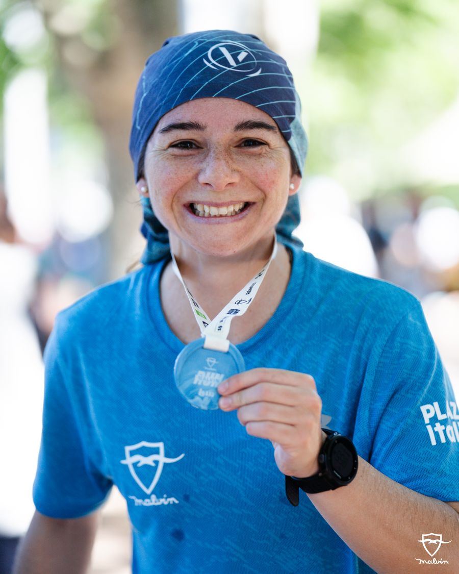 Corredora sonriendo mientras muestra su medalla finisher